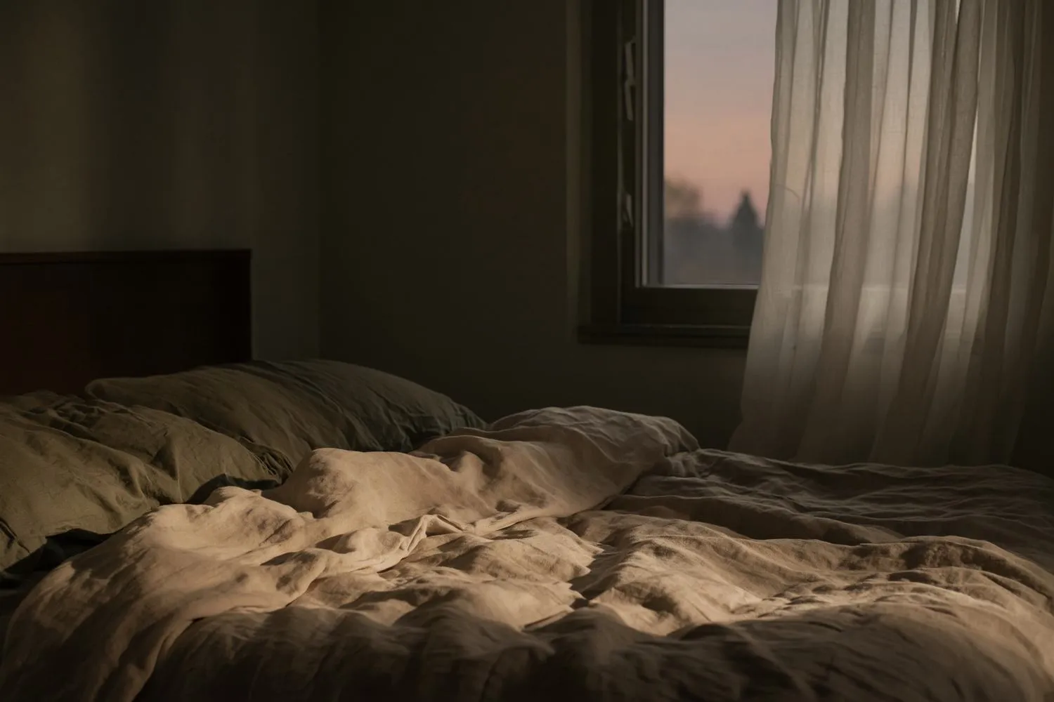 Ruhiges Schlafzimmer mit Leinenbettwäsche und gedämpftem Licht am Abend